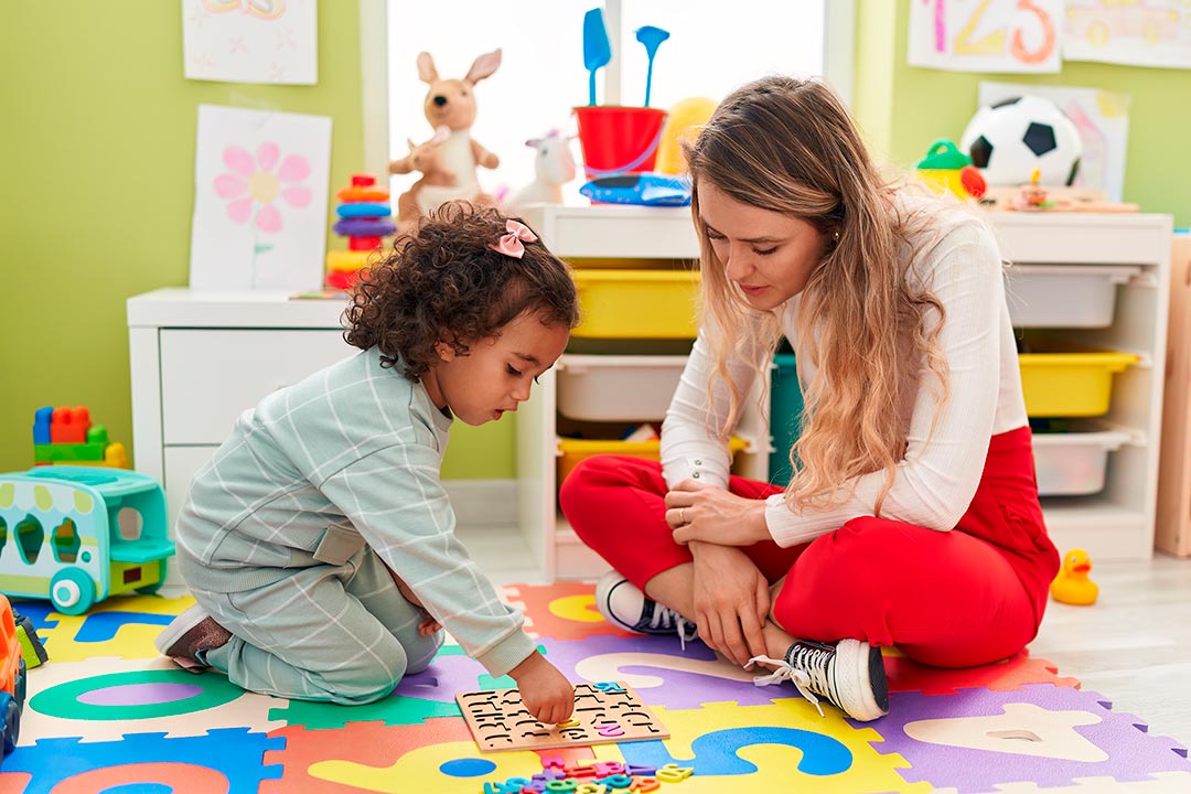 Early childhood educator with child solving puzzles